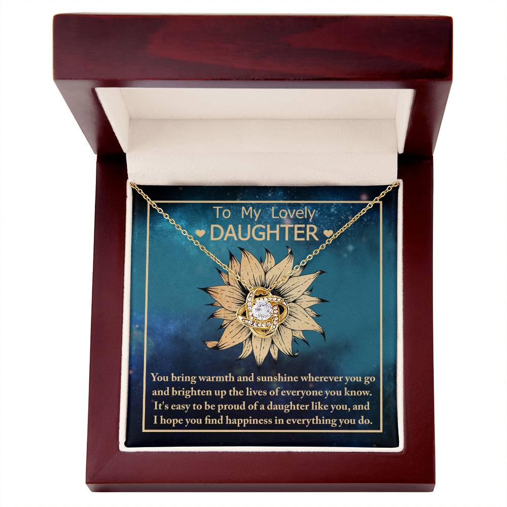 A gold sunflower pendant necklace with a cubic zirconia center is displayed in an open wooden gift box. The box's interior has a message that reads: "To Daughter, Be Proud Of - Love Knot Necklace" and a heartfelt note beneath, making it the perfect personalized gift.