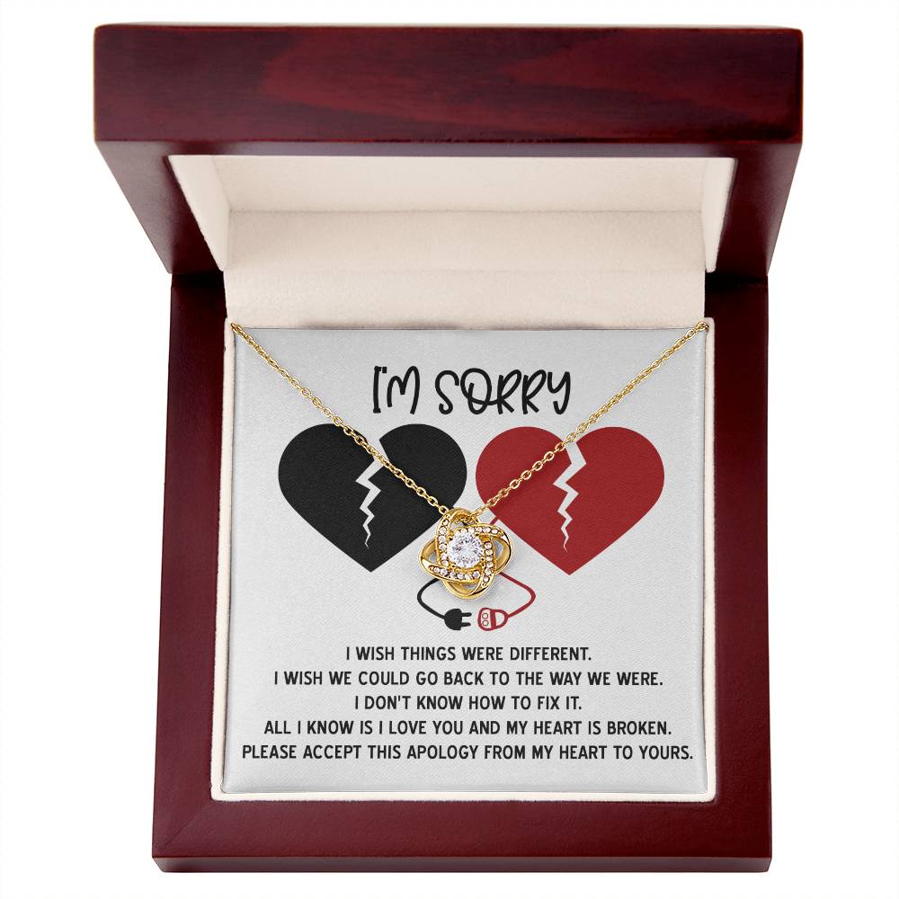 The "Sorry-Heart Is Broken - Love Knot Necklace" features an intertwined heart and infinity design, adorned with cubic zirconia crystals. It is displayed on a card with two broken hearts and a heartfelt message expressing sorrow and hope for reconciliation, all in a stunning white gold finish.