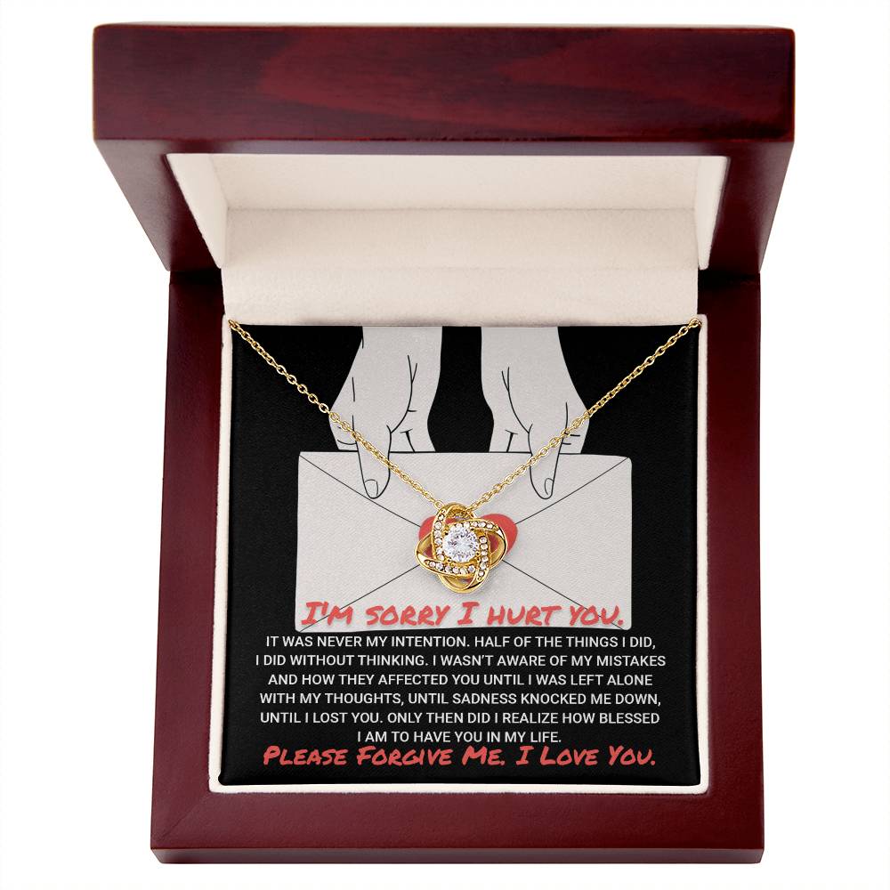 The "Sorry-Without Thinking" Love Knot Necklace, featuring cubic zirconia crystals, is elegantly displayed in an open wooden box with an apology message printed inside, making it a timeless gift.