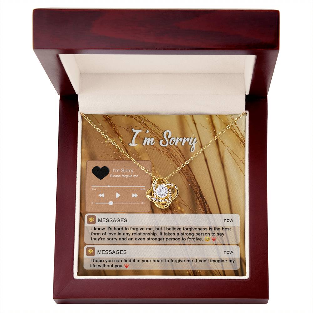 The "Sorry, Person To Forgive - Love Knot Necklace" features a gold finish and sparkling cubic zirconia crystals. It is presented on a card adorned with musical notes and icons that reads "I'm Sorry," along with heartfelt messages of apology and pleas for forgiveness.