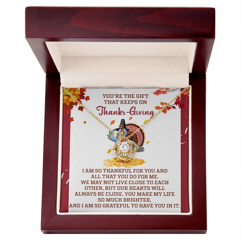 The Thanksgiving-Always Be Close - Love Knot Necklace, embellished with cubic zirconia crystals, is presented in a wooden box that includes a Thanksgiving-themed message card adorned with a turkey and autumn leaves, making it an ideal personalized gift.