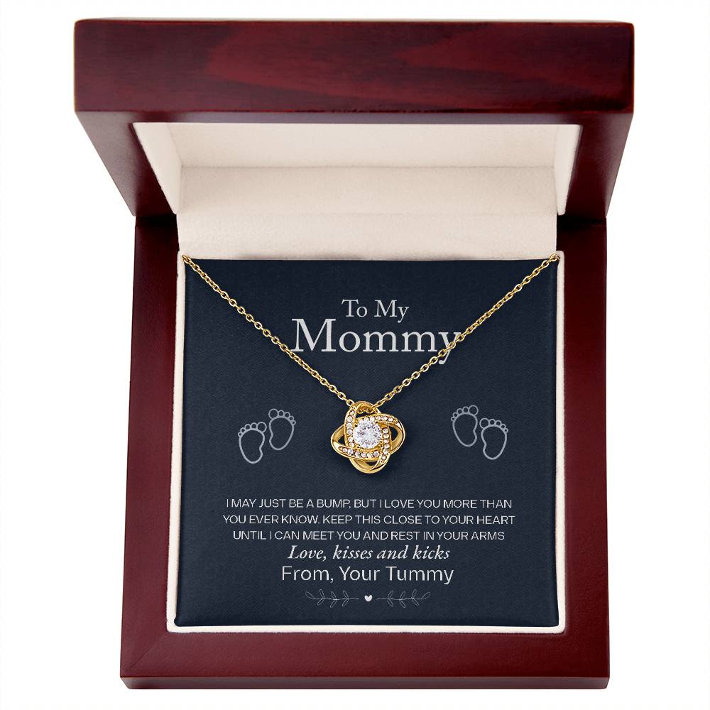 A To My Mommy, Love From Your Tummy - Love Knot Necklace with a heart-shaped pendant in a gold finish, presented in a gift box featuring a sentimental message to an expectant mother from the baby in her womb.