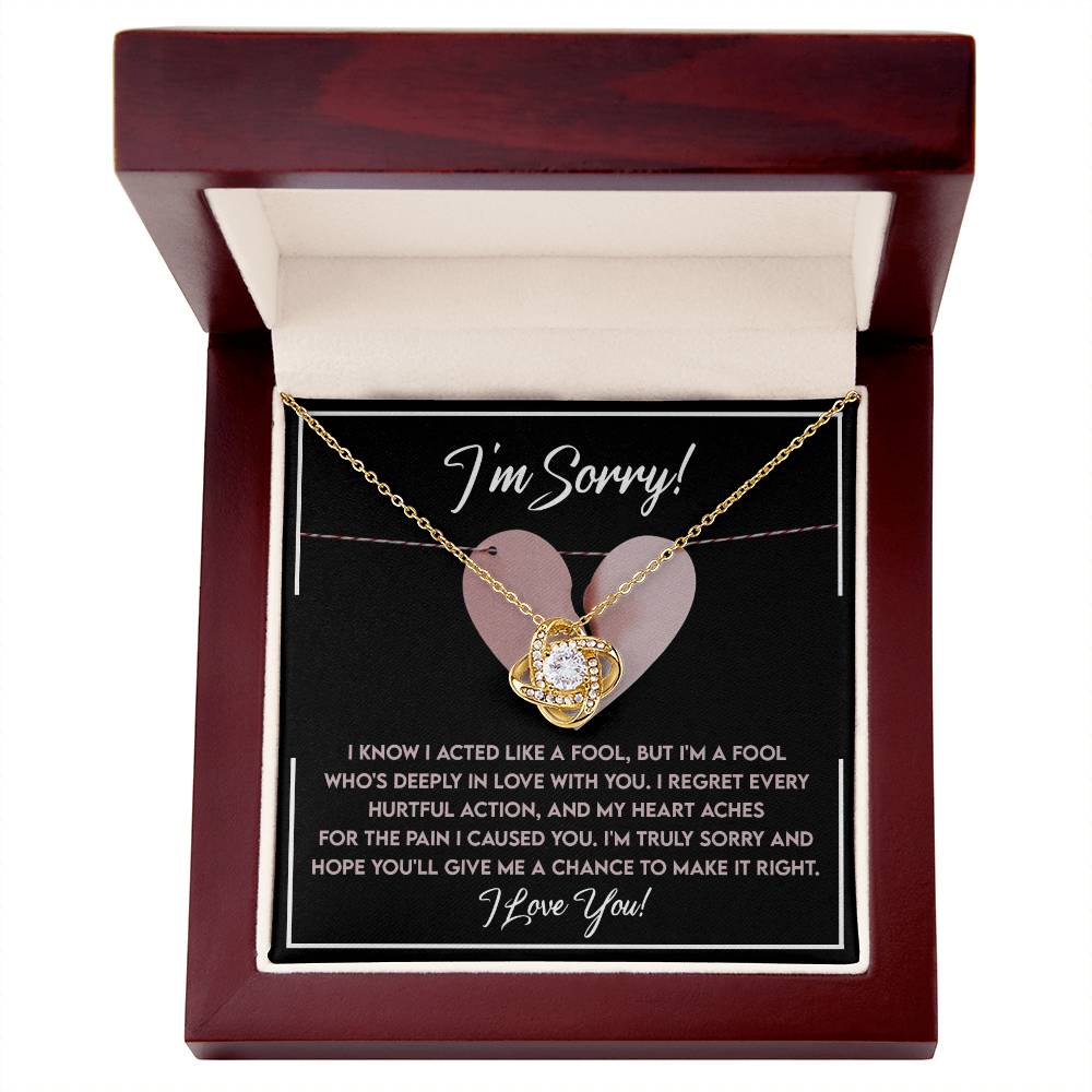 The Sorry-Deeply In Love - Love Knot Necklace showcases a gold heart-shaped pendant adorned with cubic zirconia crystals, elegantly presented in a box with a touching "I'm Sorry!" message expressing regret and affection.
