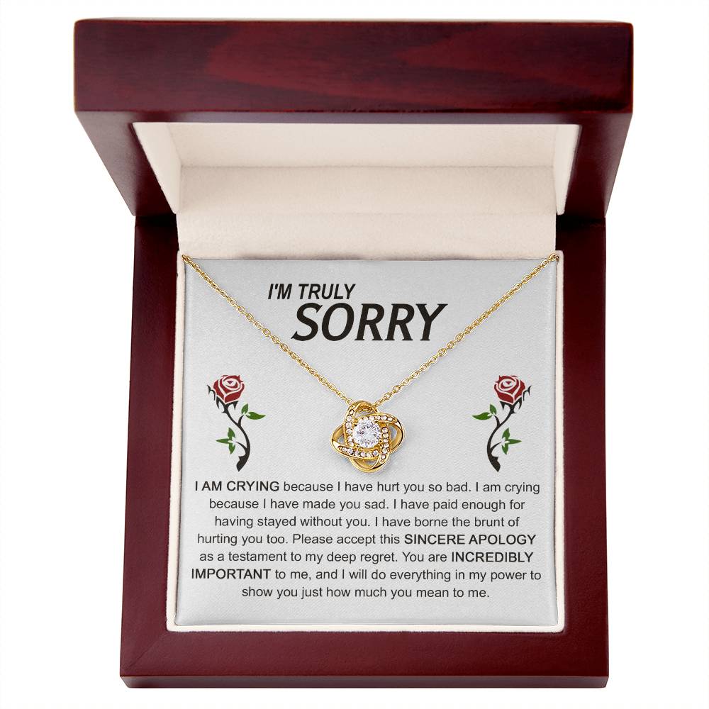 The Sorry-Made You Sad - Love Knot Necklace, crafted in silver with an interlocking design, is presented on a card featuring an apology message and accompanied by two red roses. The text conveys profound regret and vows to make things right, while the cubic zirconia crystals enhance the elegance of this heartfelt gesture.