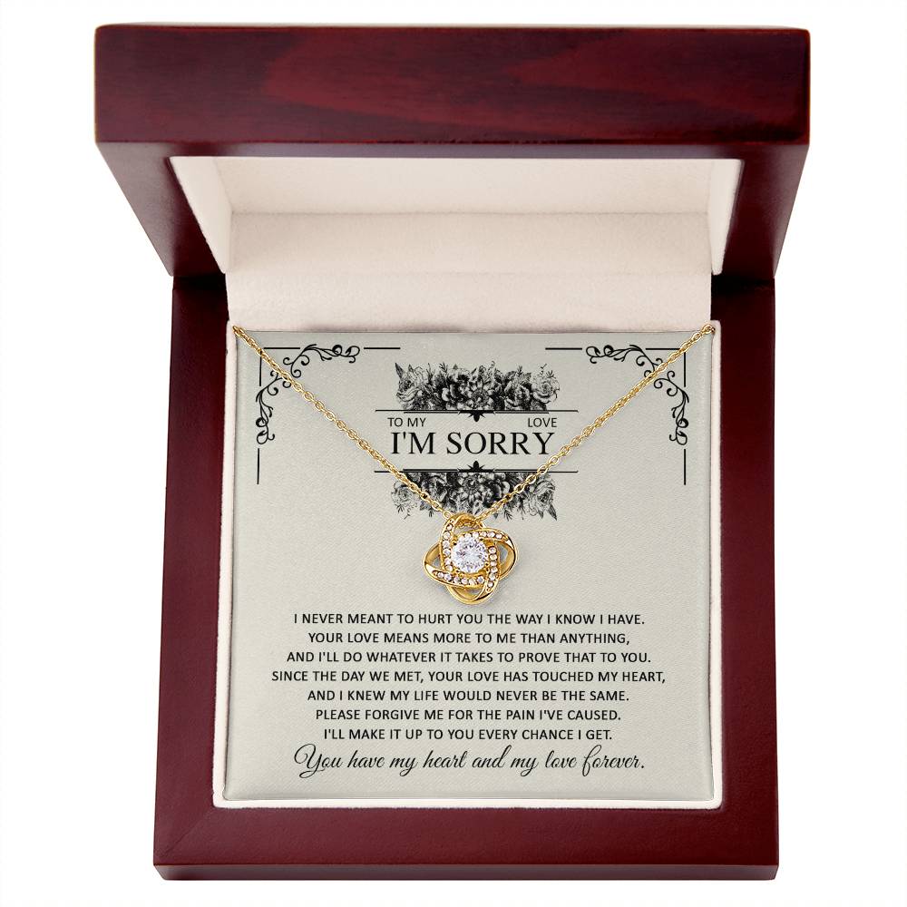 A gift box with the Sorry-Every Chance - Love Knot Necklace and an apology letter. The necklace, featuring a heart-shaped pendant with intertwined rings adorned with cubic zirconia crystals, comes in a dazzling white gold finish. The letter expresses regret and a promise of love.