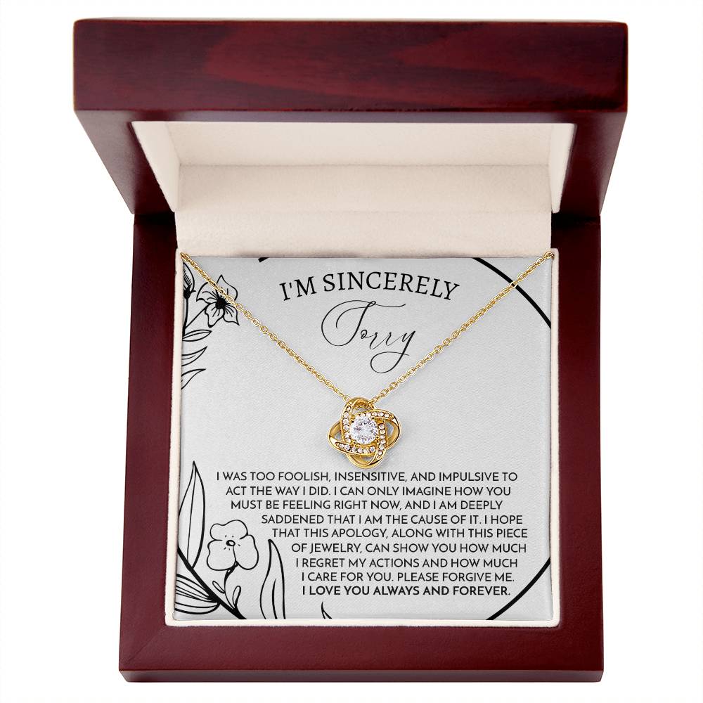 The Sorry-Care For You - Love Knot Necklace features a pendant with intertwined loops adorned with sparkling cubic zirconia crystals. It is elegantly displayed on a card that conveys an apology message, reading "I'm sincerely sorry," expressing deep regret and love.