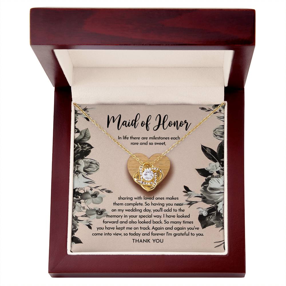 The "To Maid of Honor, My Wedding Day - Love Knot Necklace" features a heart-shaped pendant on a card titled "Maid of Honor," with a heartfelt message about milestones, love, and gratitude. The pendant is available in white gold or yellow gold finish and is adorned with sparkling cubic zirconia crystals.