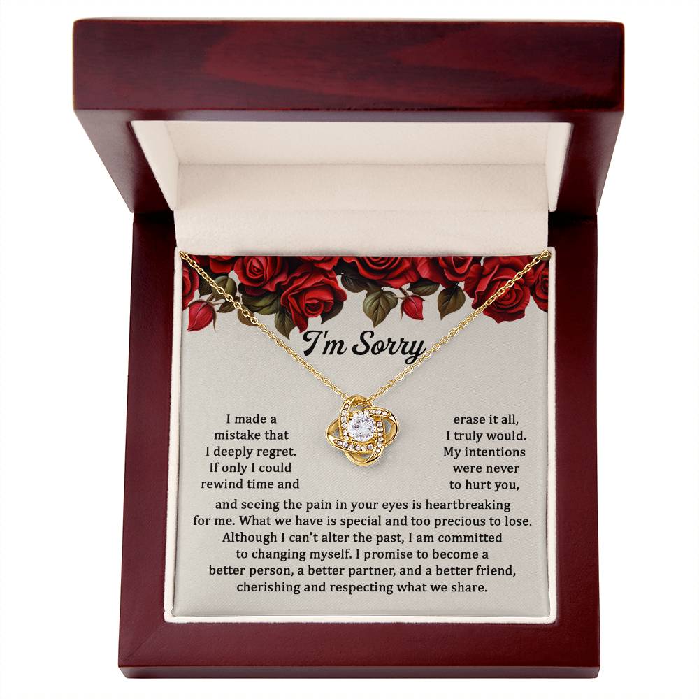 The "Sorry, Precious To Lose - Love Knot Necklace," adorned with cubic zirconia crystals, is displayed on a card featuring an apology message set against a background of red roses. The message expresses regret and a commitment to change.