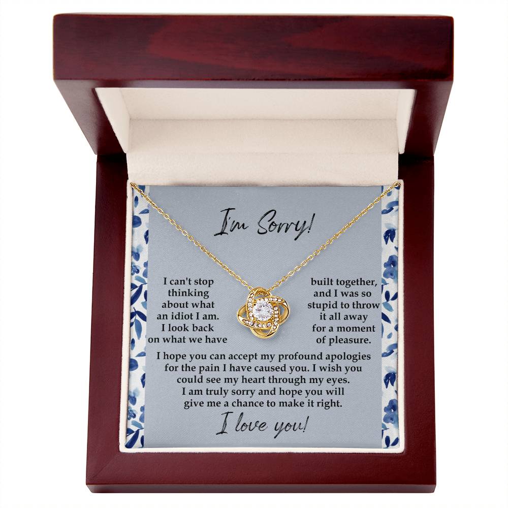 The "Sorry-Through My Eyes - Love Knot Necklace," adorned with cubic zirconia crystals and a white gold finish, is presented on a card featuring a heartfelt apology message, expressing regret for causing pain and seeking forgiveness.