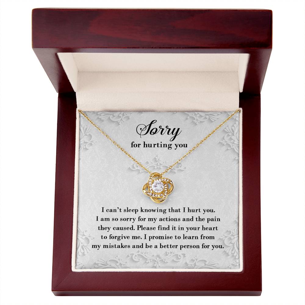 The Sorry-Can’t Sleep - Love Knot Necklace features a diamond pendant and comes in a red box with an apology message on the lid, expressing regret for causing hurt and promising to learn from mistakes. The necklace is available in either white gold or yellow gold finishes and is adorned with cubic zirconia crystals for extra brilliance.