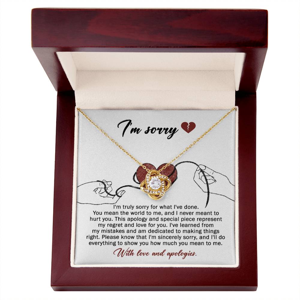 The Sorry-Mean The World - Love Knot Necklace, crafted from white gold and adorned with a heart-shaped pendant, is displayed on a card. This card conveys an apology message expressing regret and dedication to making things right, ending with "With love and apologies." The necklace is embellished with sparkling cubic zirconia crystals that add a touch of elegance.