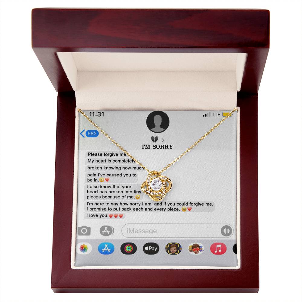 The "Sorry, Completely Broken - Love Knot Necklace" features a gold finish and sparkling cubic zirconia crystals, displayed atop a printed text message conversation that conveys an apology and expresses love.