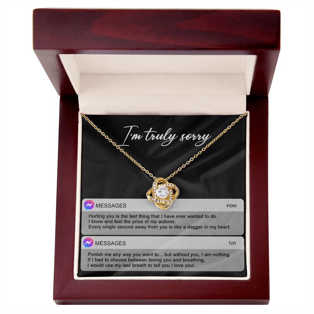 The Sorry-Away From You - Love Knot Necklace features interwoven heart pendants adorned with cubic zirconia crystals, and comes in a box with "I'm truly sorry" inscribed above. Accompanying the necklace are two text message excerpts expressing regret and love, making it an ideal personalized gift.