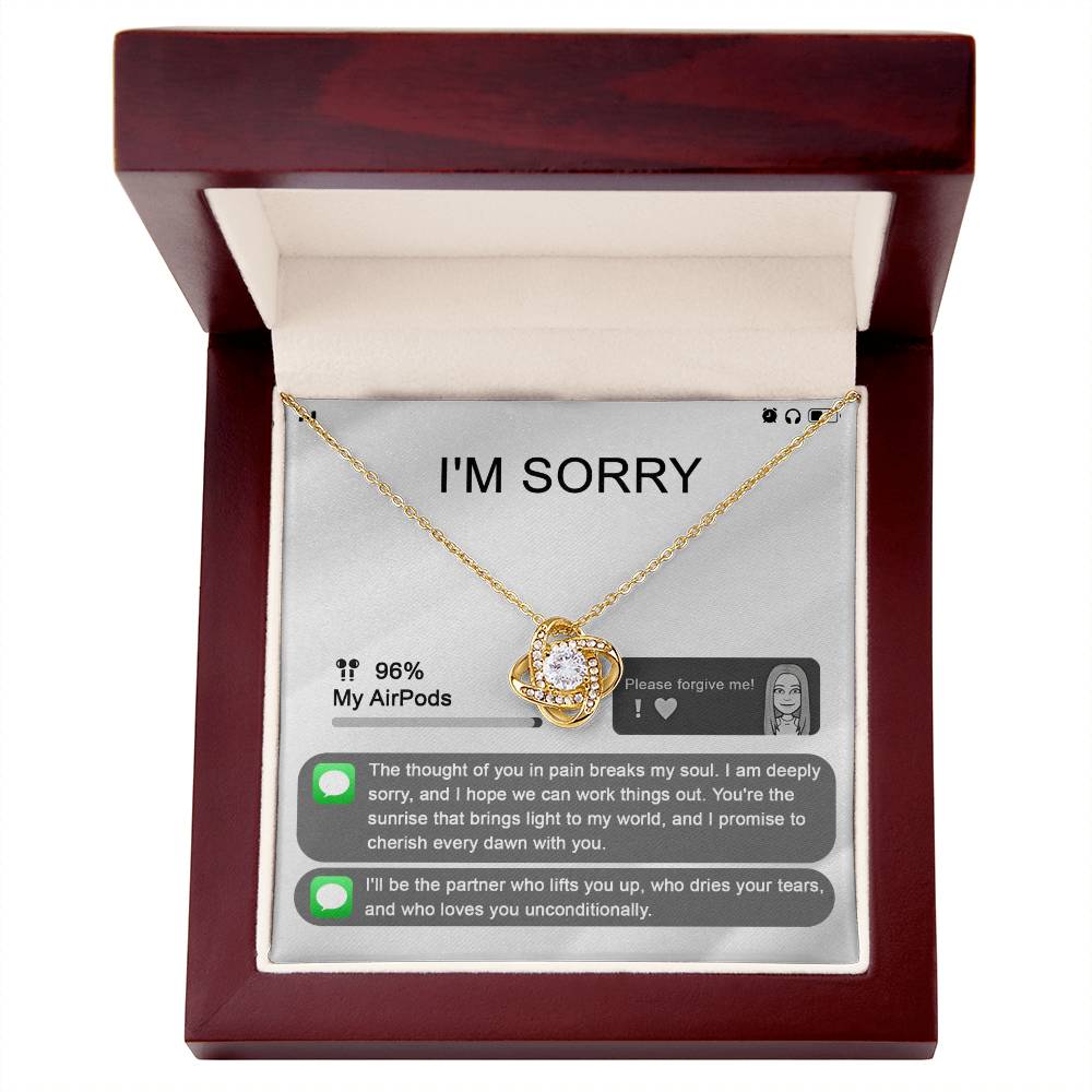 The "Sorry-Breaks My Soul - Love Knot Necklace" is a silver necklace featuring a pendant, beautifully displayed in its packaging. The front of the packaging includes a heartfelt apology message, text messages, a battery icon showing 96% for AirPods, and an illustrated figure. This intricately crafted piece is made from 14k white gold and adorned with cubic zirconia crystals.