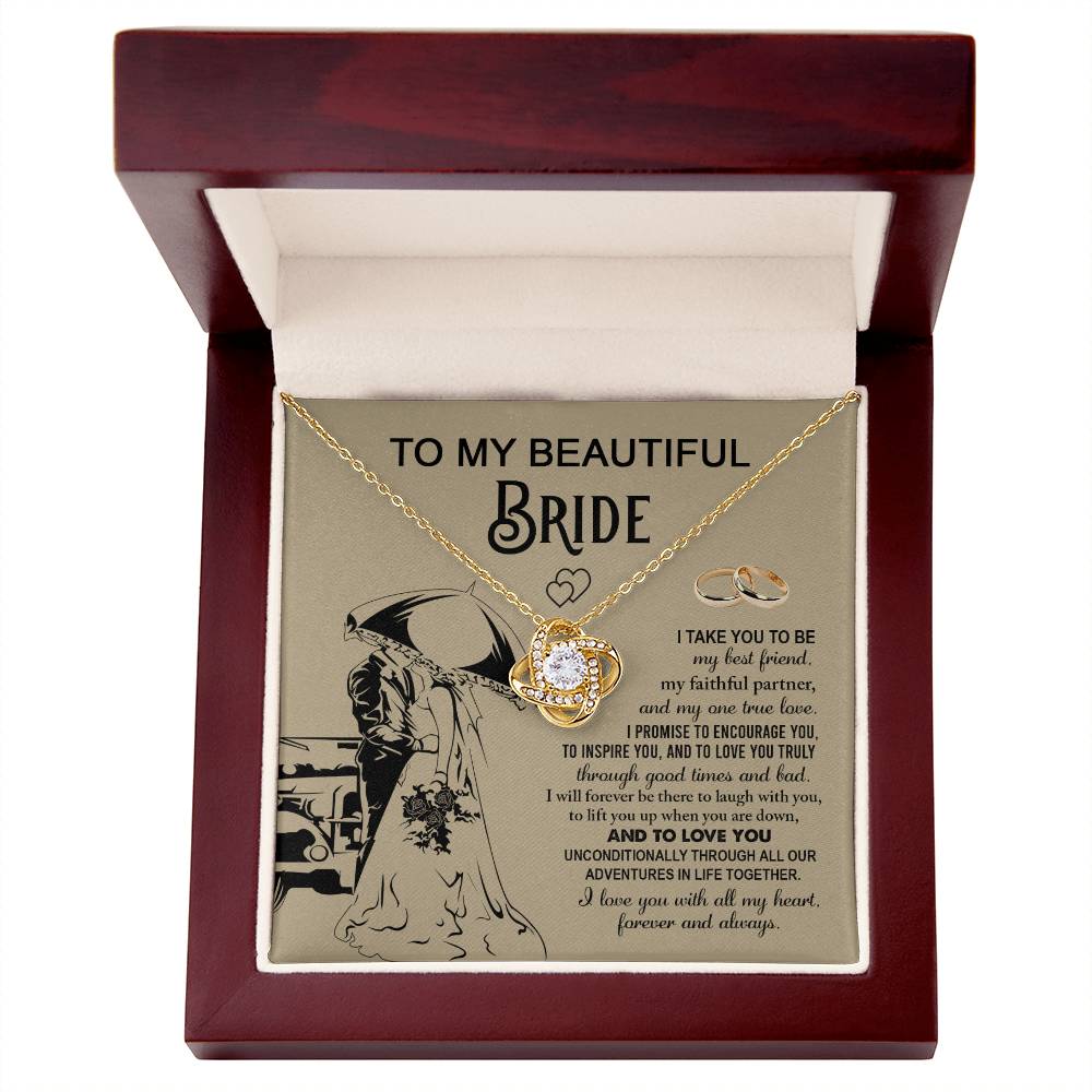 A "To My Bride, Faithful Partner - Love Knot Necklace" adorned with cubic zirconia crystals is displayed in a box. The background features a silhouette of a couple under an umbrella, two rings, and a heartfelt message to a bride, making it the perfect unique gift.