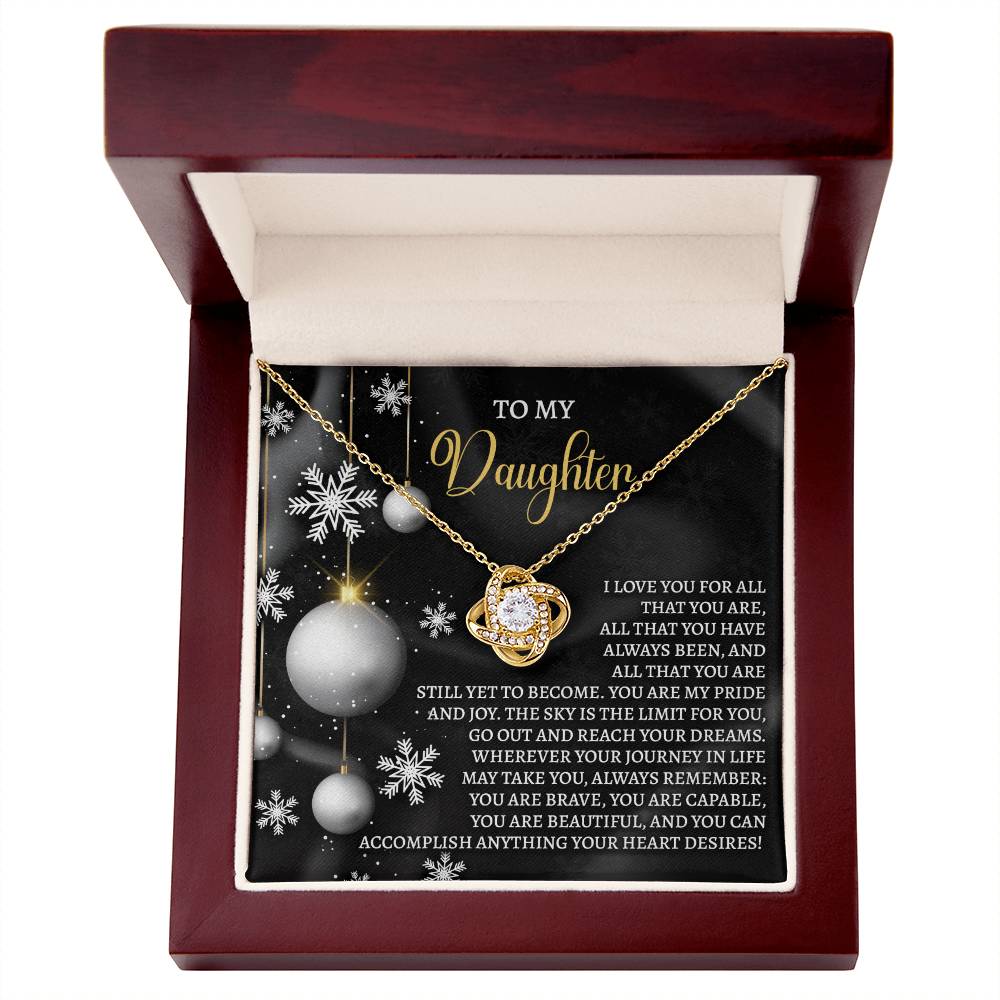 The Daughter-Pride And Joy - Love Knot Necklace is elegantly presented in a wooden box, accompanied by a decorative card featuring silver and white accents with a heartfelt message for your daughter—making it a truly personalized gift.