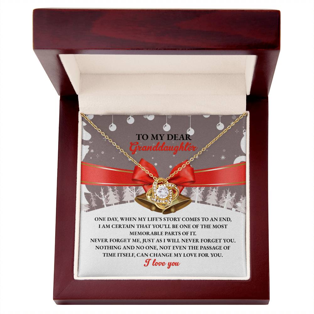 This Granddaughter-Memorable Parts - Love Knot Necklace makes a personalized gift, featuring a circular pendant nestled in a wooden box with an engraved message for a granddaughter inside. The cubic zirconia adds a touch of sparkle to this heartfelt keepsake.