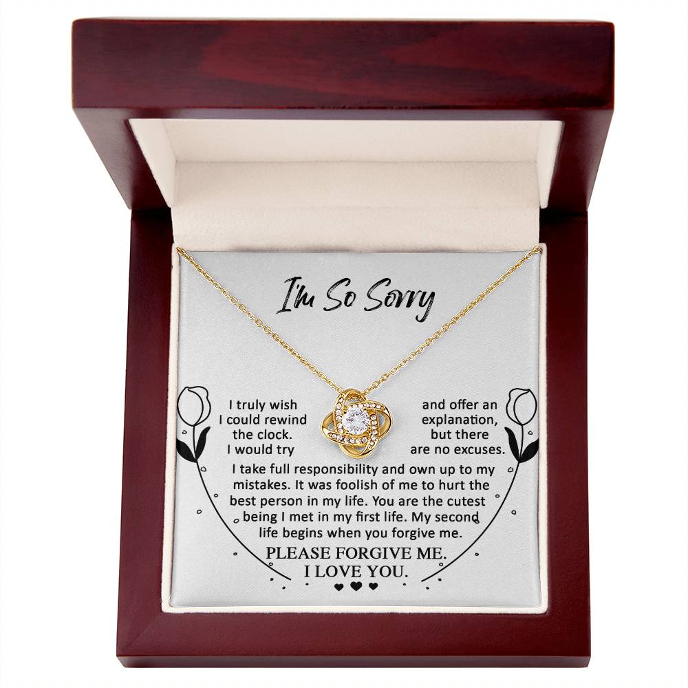 The "Sorry-My First Life - Love Knot Necklace," adorned with cubic zirconia crystals, is placed inside an open wooden box. The box contains an apology note expressing regret and seeking forgiveness, symbolizing an unbreakable bond.