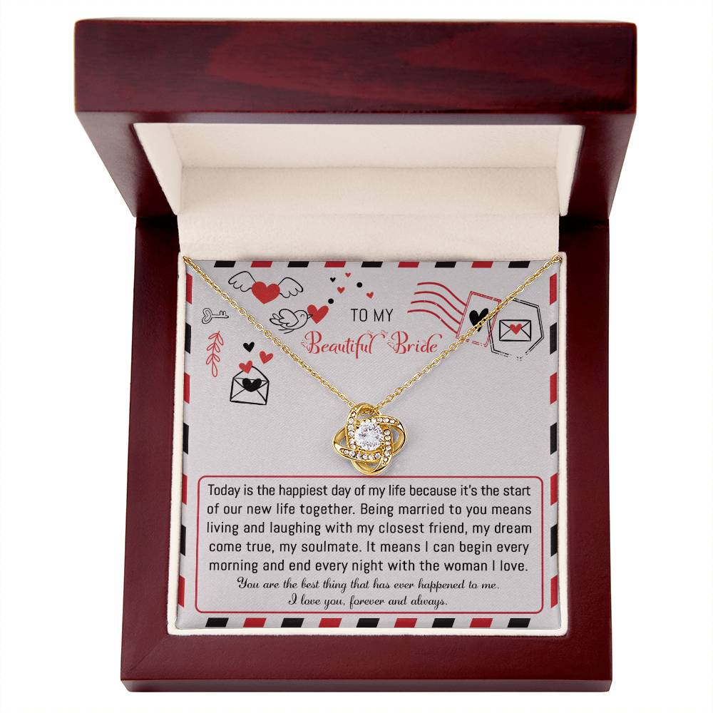 The "To Bride, The Happiest Day - Love Knot Necklace," beautifully crafted from 14k white gold and adorned with cubic zirconia crystals, is elegantly presented in a box featuring a heartfelt message for the bride, expressing love and joy for their life together.