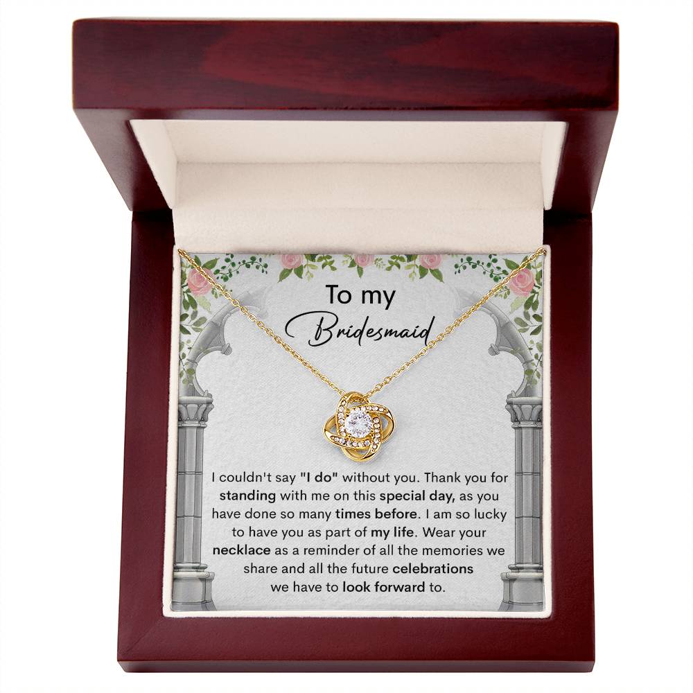 A personalized gift, the *To My Bridesmaid, Standing With Me - Love Knot Necklace* with cubic zirconia crystals, is displayed on a card that expresses gratitude to a bridesmaid, highlighting the importance of her support on the special day.