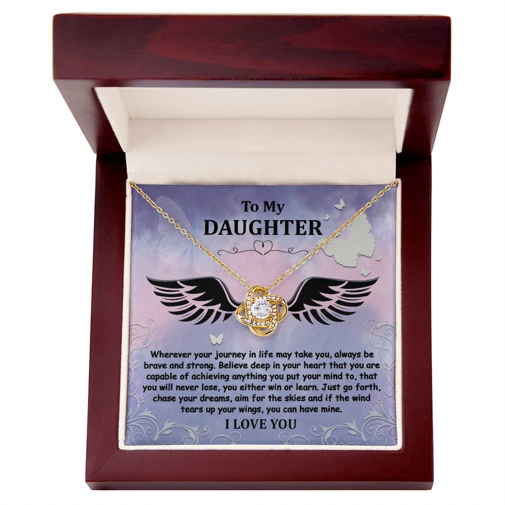 The "To Daughter, Brave And Strong - Love Knot Necklace" features a gold finish and a Cubic Zirconia pendant, beautifully displayed in a box. The box contains a heartfelt message titled "To My Daughter," encouraging bravery, strength, and the pursuit of dreams, and concludes with the words "I LOVE YOU.