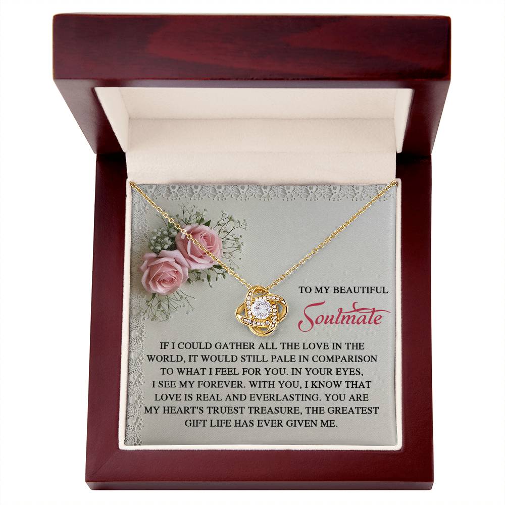 The Soulmate-Given Me - Love Knot Necklace features a circular, white gold-finished pendant adorned with cubic zirconia crystals. It's elegantly packaged in a wooden box surrounded by pink roses with an inscription about love and soulmates.