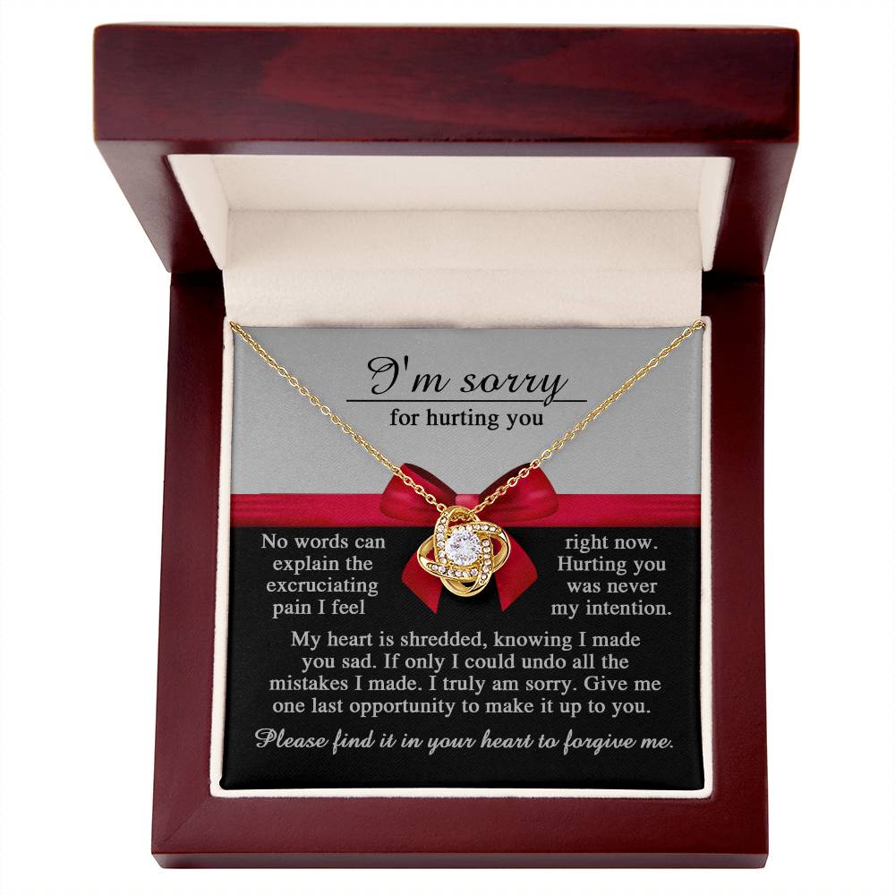 A "Sorry-Made You Sad" jewelry gift box containing a Love Knot Necklace adorned with cubic zirconia crystals and a card that reads, "I'm sorry for hurting you" with an apology message.