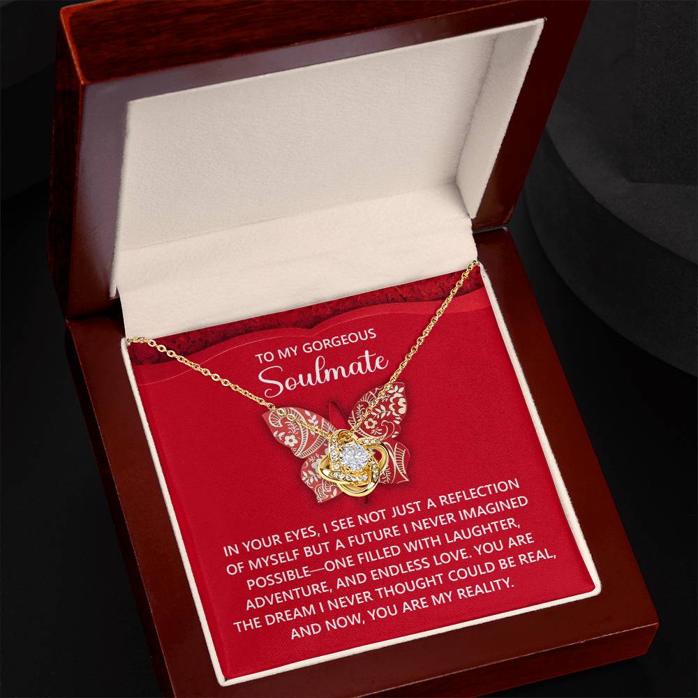 The Soulmate-My Reality Love Knot Necklace, set in a jewelry box and adorned with shimmering cubic zirconia crystals, comes with a heartfelt red and white message for a soulmate.