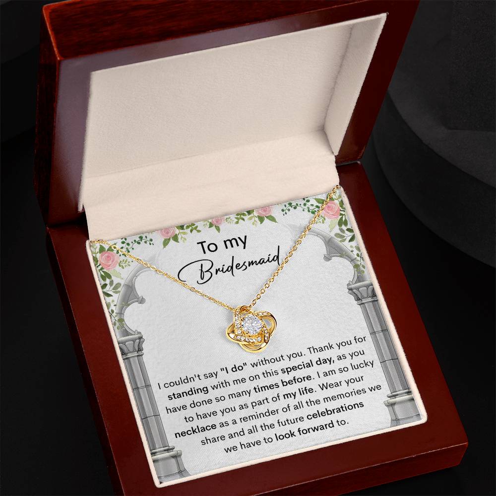 A personalized gift, the *To My Bridesmaid, Standing With Me - Love Knot Necklace* with cubic zirconia crystals, is displayed on a card that expresses gratitude to a bridesmaid, highlighting the importance of her support on the special day.