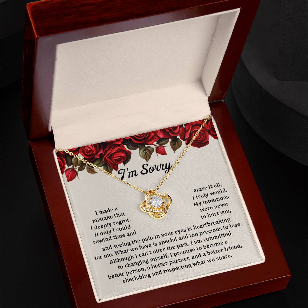 The "Sorry, Precious To Lose - Love Knot Necklace," adorned with cubic zirconia crystals, is displayed on a card featuring an apology message set against a background of red roses. The message expresses regret and a commitment to change.