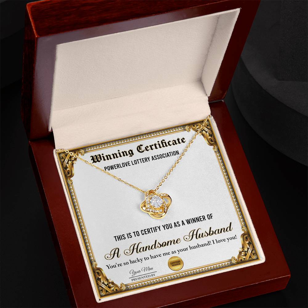 A "To Wife, Winning Certificate - Love Knot Necklace" is displayed against a certificate text background reading, "Winning Certificate - Powerlove Lottery Association - A Handsome Husband," featuring shimmering cubic zirconia crystals and an elegant gold finish.