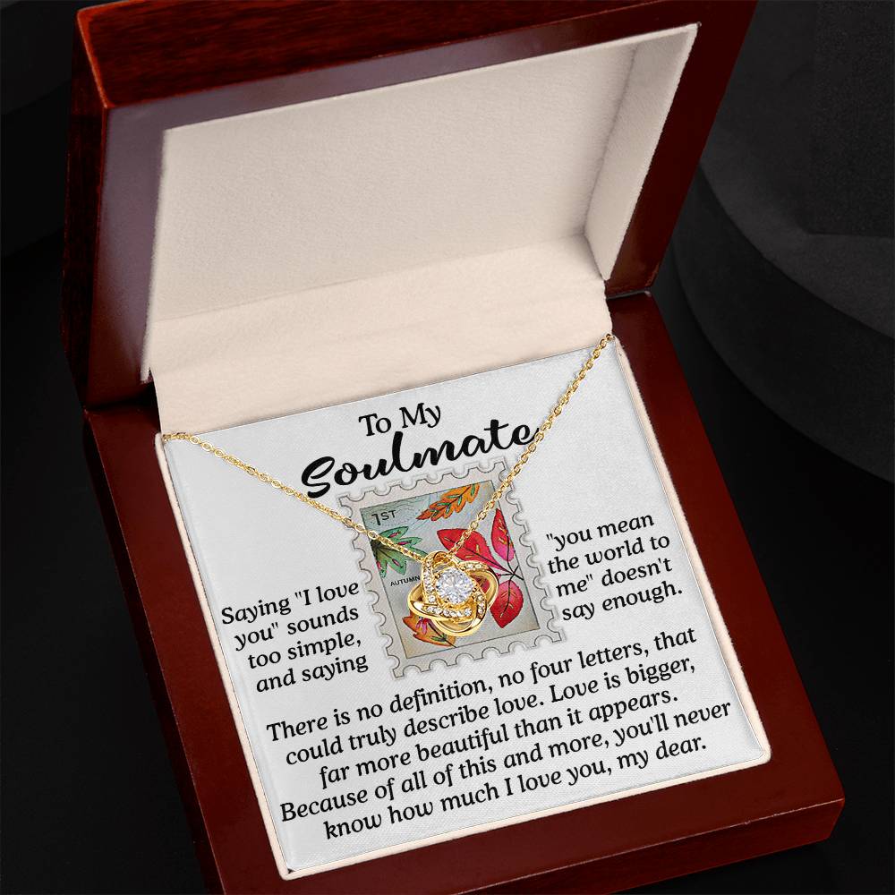 In an open box, the Soulmate-Far More Beautiful Love Knot Necklace shines with its heart pendant, symbolizing unbreakable bonds. Inside the lid, a heartfelt message expresses love's profound depth beyond words to a soulmate, making it an unforgettable personalized gift.