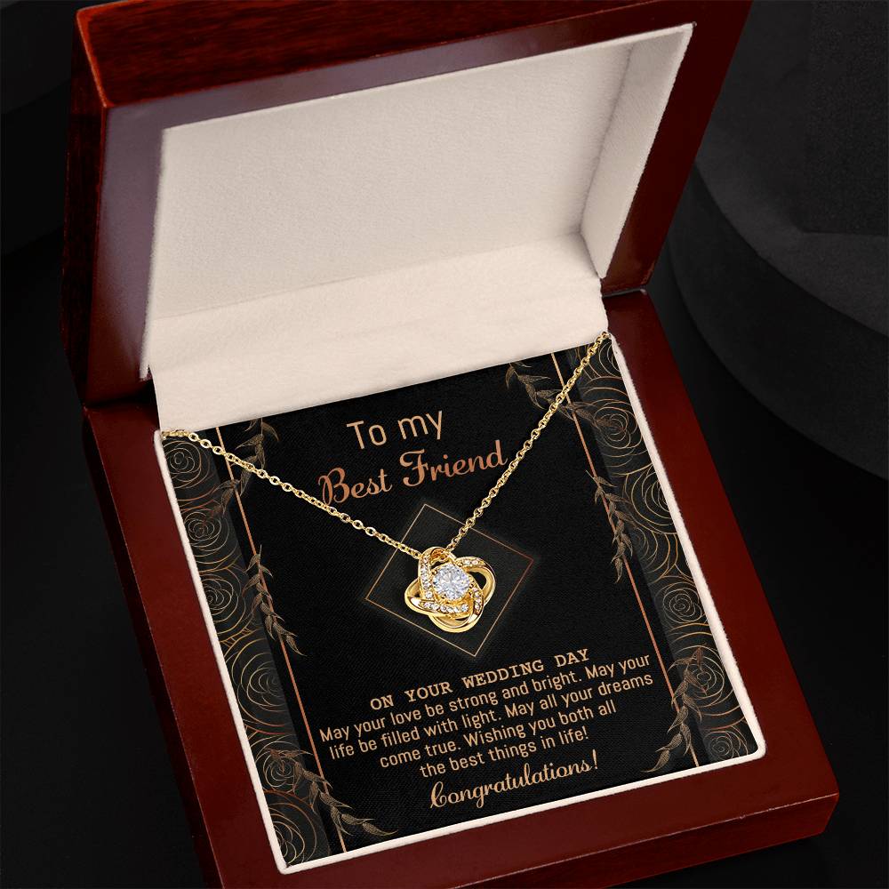 A "To Best Friend Wedding, Strong And Bright - Love Knot Necklace" adorned with cubic zirconia crystals is elegantly displayed on a black card that reads, "To my Best Friend on your wedding day. Congratulations!" The card features a decorative gold border and highlights the necklace's white gold or yellow gold finish options.