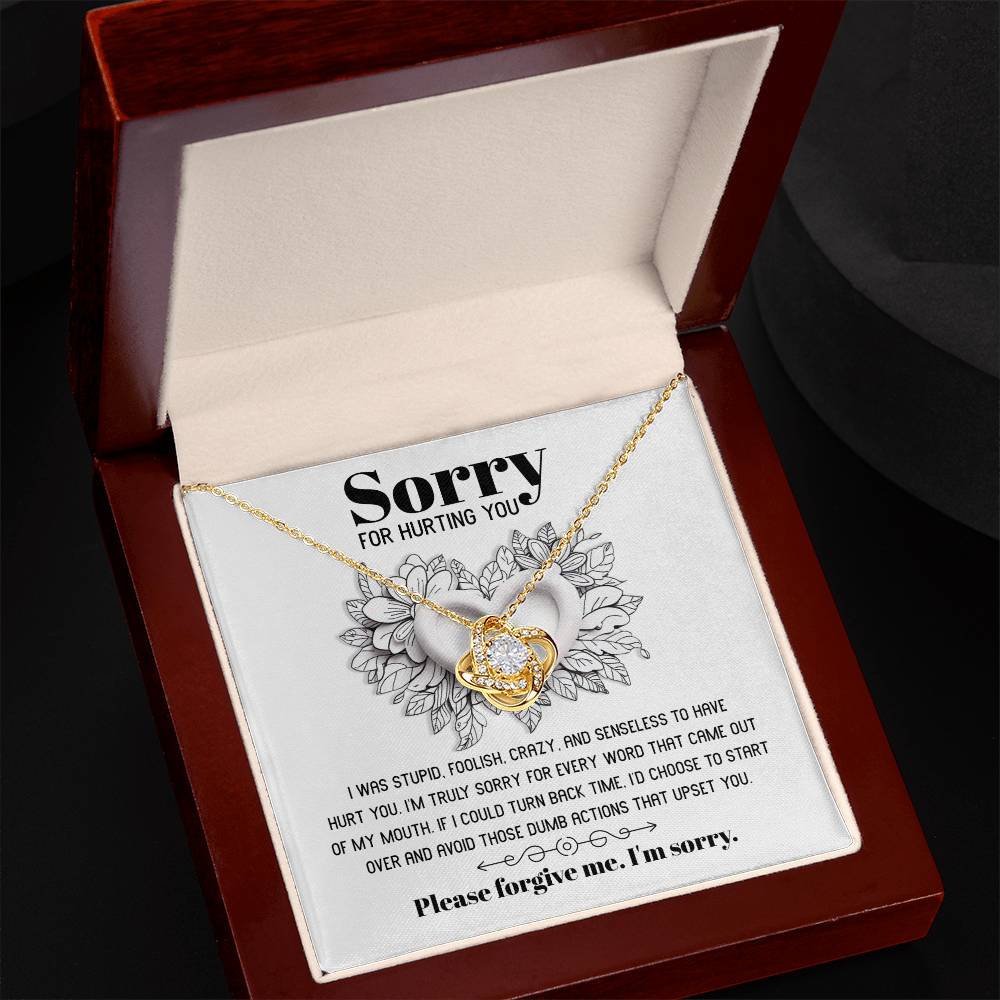 The Sorry-Turn Back Time - Love Knot Necklace, adorned with sparkling cubic zirconia crystals and featuring an intertwined pendant, is displayed on a card with the heartfelt apology message, "Sorry for hurting you," symbolizing an unbreakable bond and a request for forgiveness.