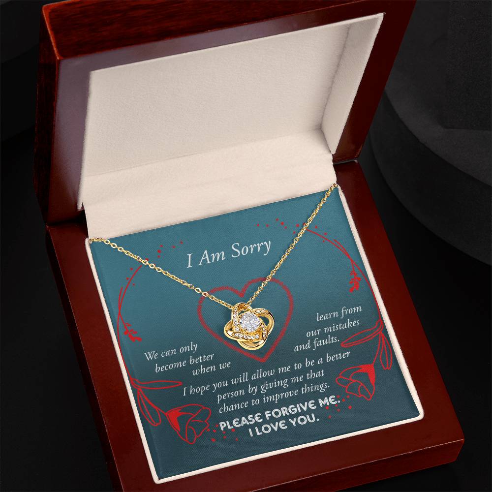 The Sorry-Mistakes And Faults - Love Knot Necklace, featuring a heart-shaped pendant with sparkling cubic zirconia set in white gold, is elegantly presented in a box adorned with the words "I Am Sorry" and a heartfelt apology message.