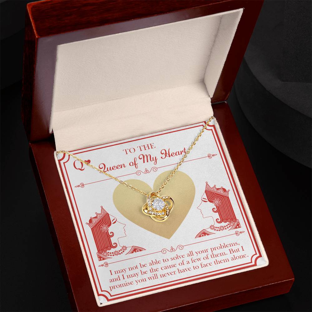 The "To Wife, The Queen - Love Knot Necklace," an exquisite gold heart-shaped necklace featuring a central diamond pendant, is showcased inside an open, dark wooden jewelry box. The lid of the box bears the message, "To the Queen of My Heart," with an illustration of a queen's profile on either side of a heart—making it a beautifully personalized gift.