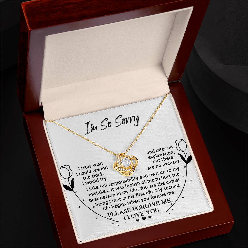 The Sorry-My First Life - Love Knot Necklace is displayed in an open red box. The inside lid reads "I'm So Sorry" and includes a heartfelt apology message. This elegant gold heart-shaped necklace features a flower design and shimmers with its gold finish, making it even more special for the one you adore.