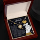 The "Soulmate-Look At You - Love Knot Necklace" features a heart-shaped, gold-finished pendant with cubic zirconia crystals. It comes in a jewelry box with a card displaying romantic text and charming graphics of hearts and hands.