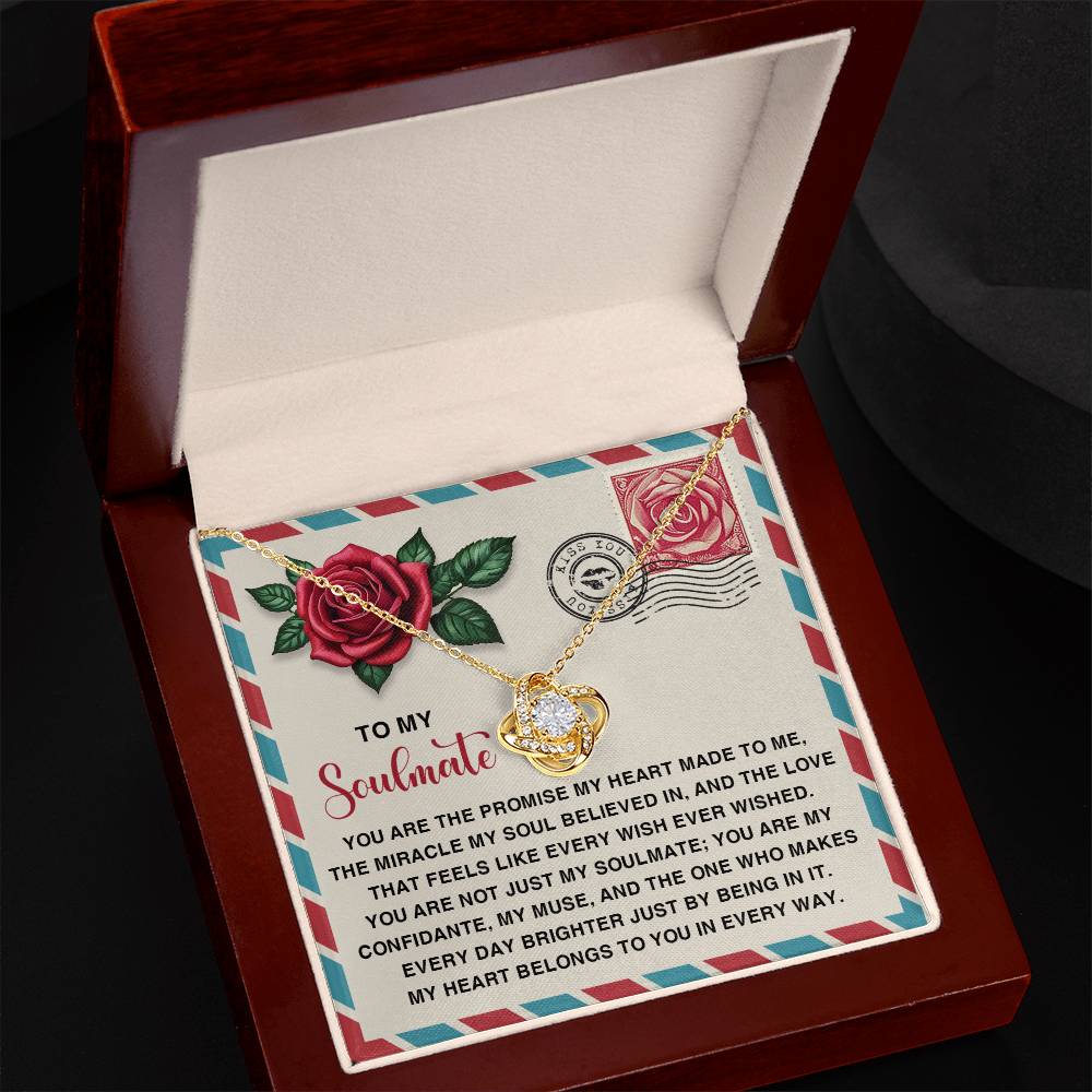 The Soulmate-Made To Me Love Knot Necklace features a heart-shaped pendant in a gift box. It sparkles with cubic zirconia embellishments and includes a note that reads, "To my Soulmate," along with a heartfelt dedication.