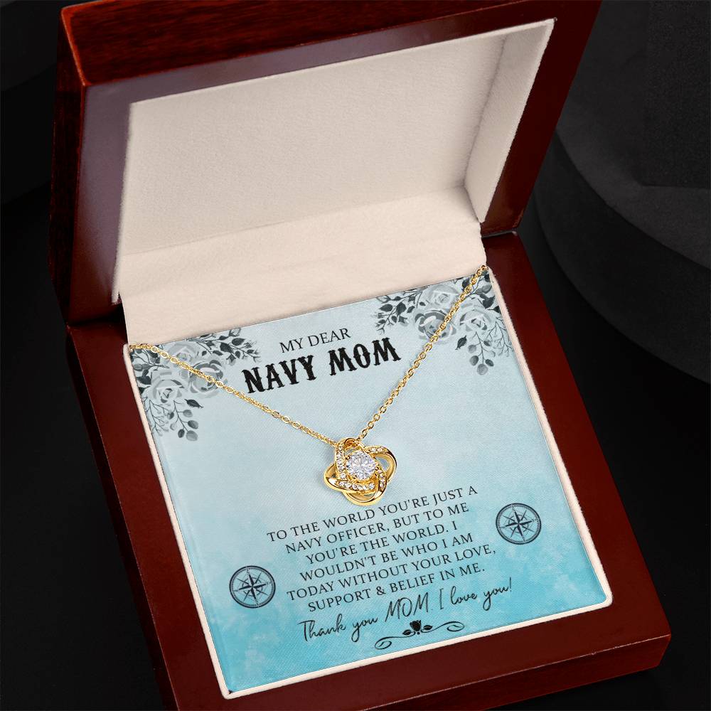An open jewelry box displaying a My Dear Navy Mom, To The World You're Just A Navy Officer - Love Knot Necklace with cubic zirconia crystals, inscribed with a message dedicated to a navy mom, expressing appreciation and love from ShineOn Fulfillment.