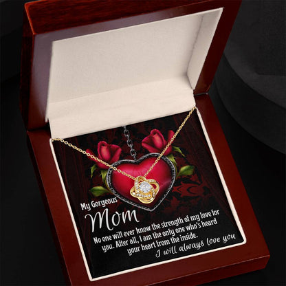 The "Almost Sold Out" To Mom, Heard Your Heart - Love Knot Necklace, adorned with sparkling cubic zirconia crystals and featuring a heartfelt message for "Mom" on the inside lid, is displayed in an open jewelry box. This gold heart-shaped necklace with a crystal pendant makes for an elegant and sentimental surprise.
