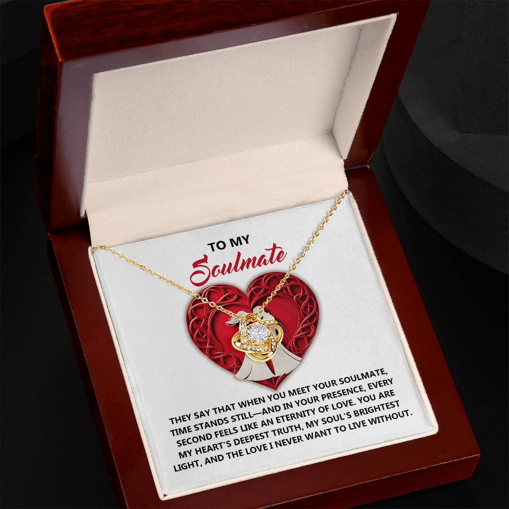 The Soulmate-Deepest Truth Love Knot Necklace showcases a heart-shaped pendant with cubic zirconia, elegantly housed in a box. Its gold finish enhances its allure, complemented by an inscription about love and soulmates.