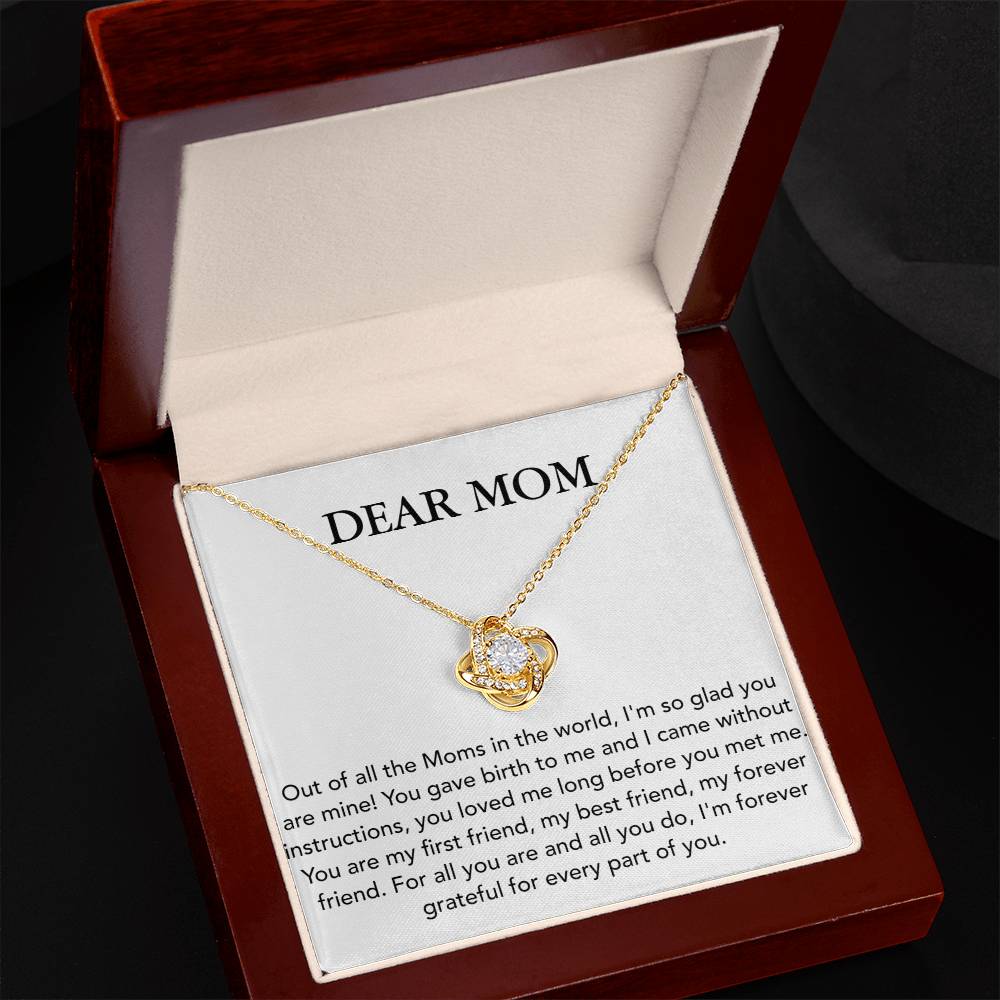 A 'Dear Mom, Out of All The Moms In The World - Love Knot Necklace' from ShineOn Fulfillment featuring a heart-shaped pendant adorned with Cubic Zirconia Crystals is showcased inside a gift box with an affectionate message dedicated to 'mom'.