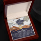 The Granddaughter-Have Mine - Love Knot Necklace, featuring a white gold finish and dazzling cubic zirconia crystals, is presented in a wooden box. Inside, an elegantly displayed card with leaf patterns holds a heartfelt message for a granddaughter.