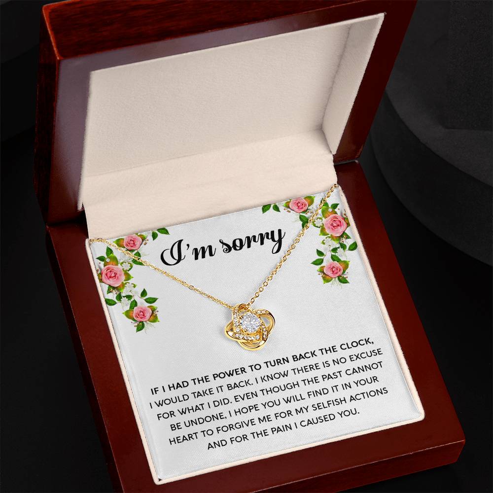 The "Sorry, Make It Right - Love Knot Necklace," featuring a silver intertwined knot pendant adorned with cubic zirconia crystals, is beautifully displayed in a box. The text on the box reads, "I’m sorry," with an apology message below, framed by a floral border in the top corners.