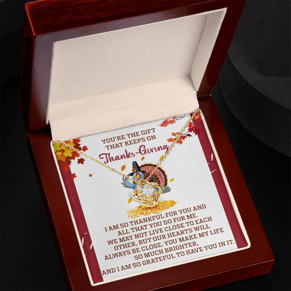 Present a jewelry box containing the Thanksgiving-Always Be Close - Love Knot Necklace, embellished with dazzling cubic zirconia crystals, accompanied by a message card featuring Thanksgiving-themed text and decorations, ideal for a personalized gift.