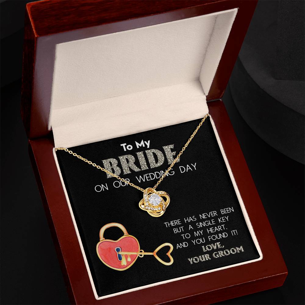 A "To My Bride, A Single Key - Love Knot Necklace" adorned with cubic zirconia crystals is displayed against a background with text that reads, "To My Bride On Our Wedding Day" and "There has never been but a single key to my heart, and you found it! Love, Your Groom.