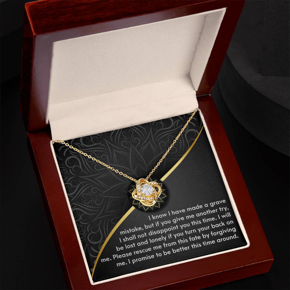 The Sorry-Turn Your Back - Love Knot Necklace, featuring a gold pendant with cubic zirconia crystals in a flower shape, is placed inside a dark wood jewelry box with a heartfelt message printed on the interior lid.