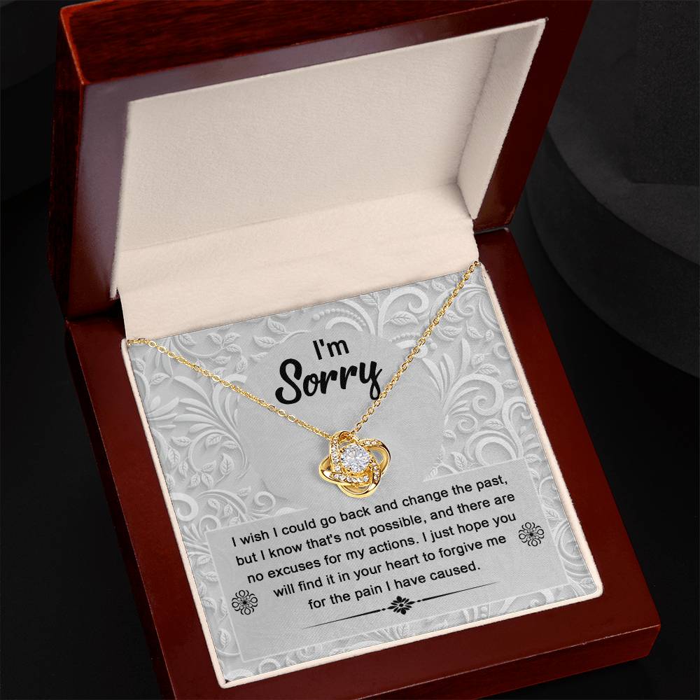 The Sorry-Change The Past - Love Knot Necklace, featuring intertwined hearts embellished with sparkling cubic zirconia crystals on a gold chain, is presented in a box along with a heartfelt note that says "I'm Sorry" and includes an apology message. This personalized gift encapsulates both elegance and sincerity.