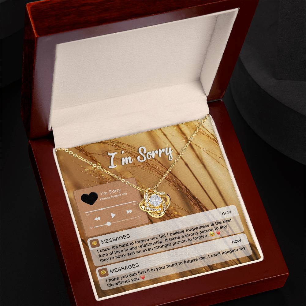 The "Sorry, Person To Forgive - Love Knot Necklace" features a gold finish and sparkling cubic zirconia crystals. It is presented on a card adorned with musical notes and icons that reads "I'm Sorry," along with heartfelt messages of apology and pleas for forgiveness.